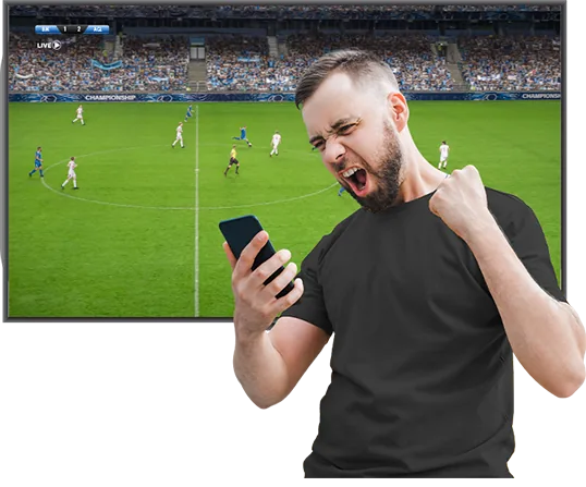 Aficionado celebra con el teléfono en la mano frente a una pantalla que transmite un partido de fútbol